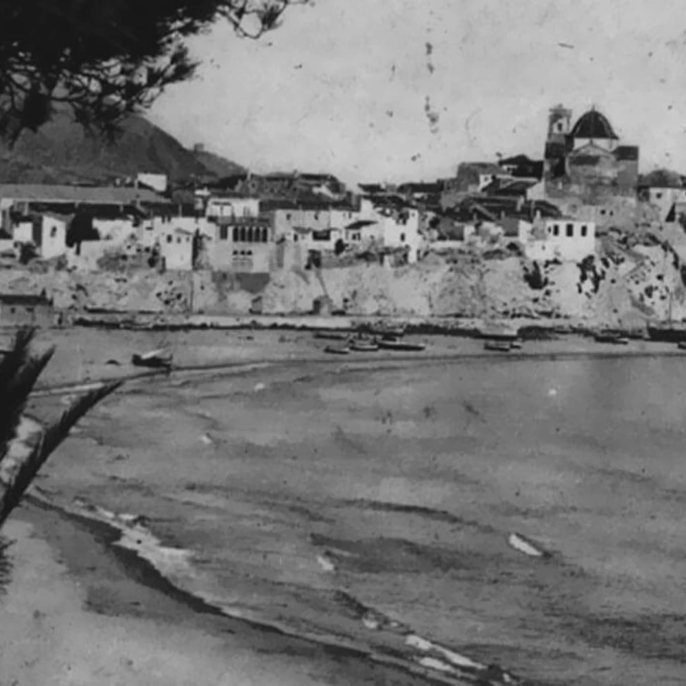 Vista en blanco y negro de un puerto con barcos y edificios en la costa.