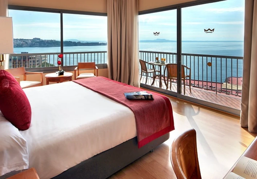 Habitaci&oacute;n de hotel con cama y balc&oacute;n frente al mar, vista panor&aacute;mica