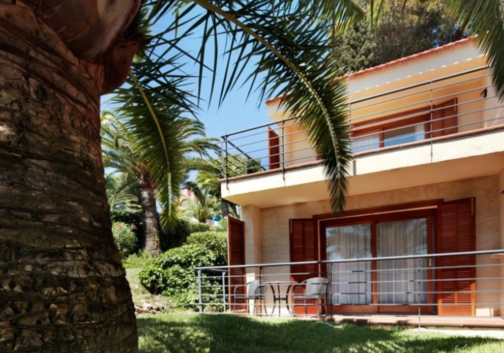 Casa blanca con balcones y palmeras en jard&iacute;n tropical, vista exterior