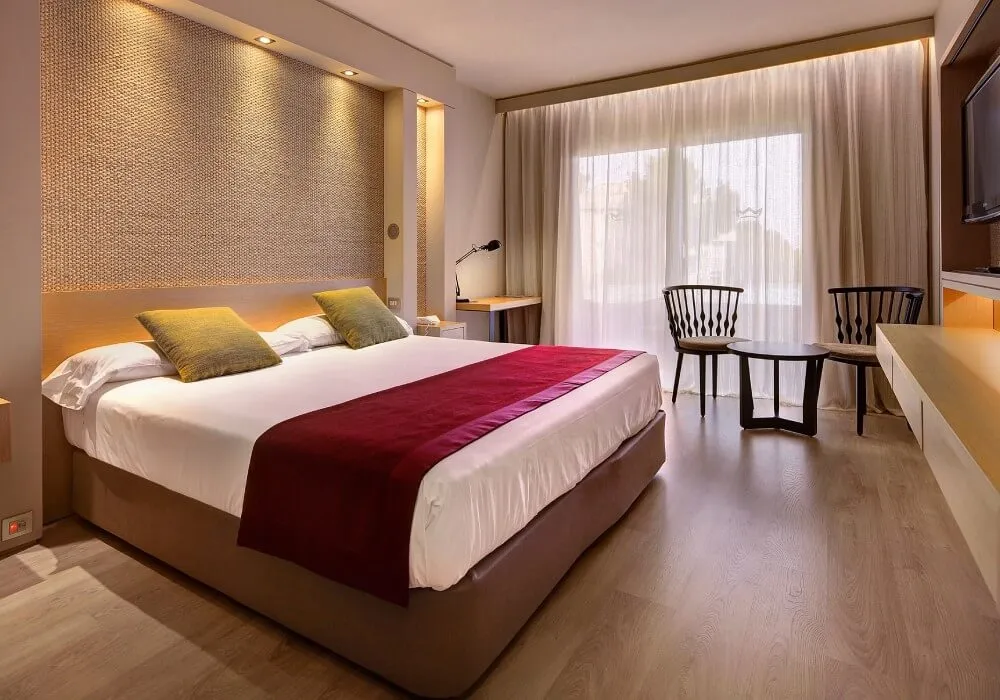 Dormitorio moderno con cama, cortinas y sillas junto a la ventana