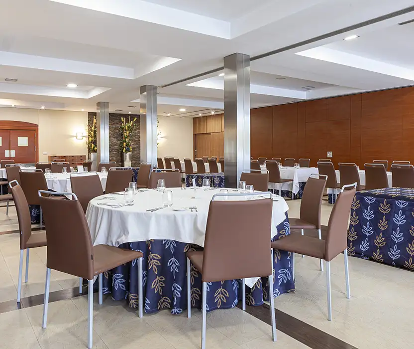 Sala de reuniones con mesas con mantel blanco y sillas en un hotel.