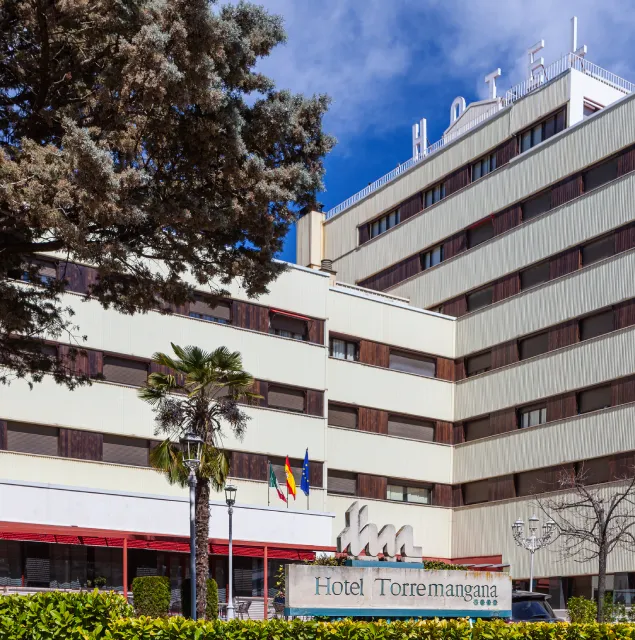 Fachada del Hotel Torremangana con palmeras, bandera y edificio de varios pisos