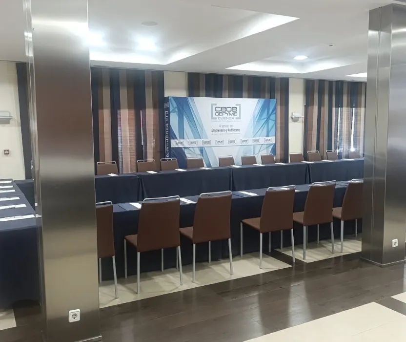 Sala de conferencias con mesas y sillas, cartel de &ldquo;Canal ECPyme&rdquo; al fondo.