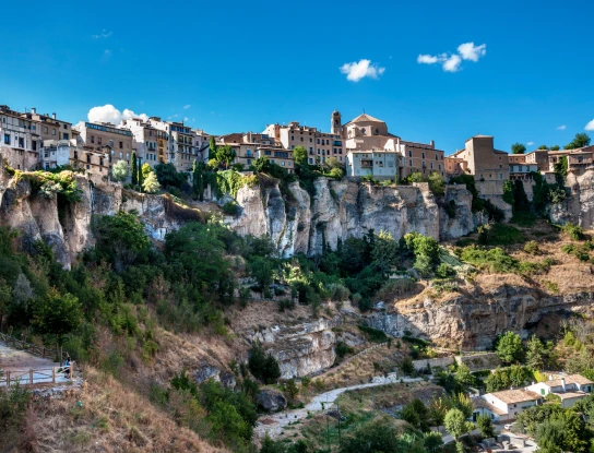Pueblo en acantilado con casas y vegetaci&oacute;n bajo cielo azul