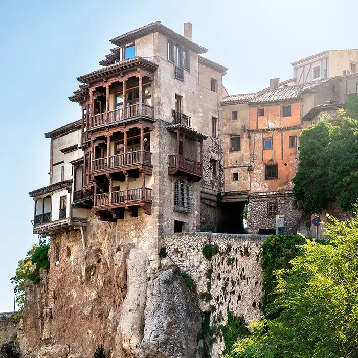 Casas antiguas en roca con balcones de madera, cielo azul y vegetación