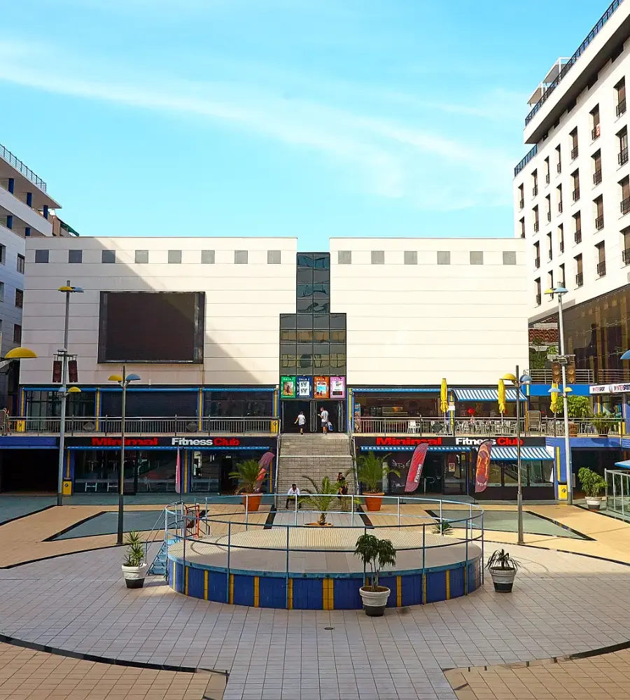 Patio con fuente circular y edificios comerciales, con cielo despejado