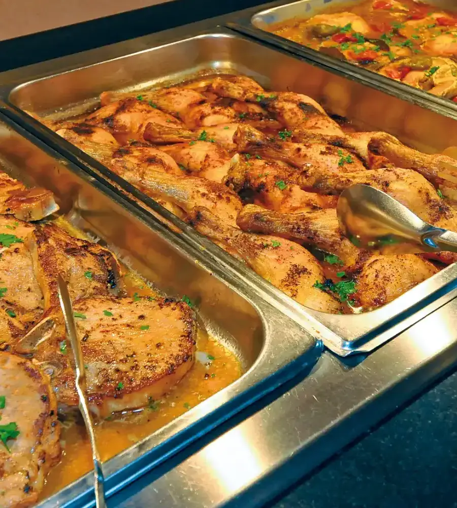 Bandejas con pollo asado y salsa, con perejil picado.