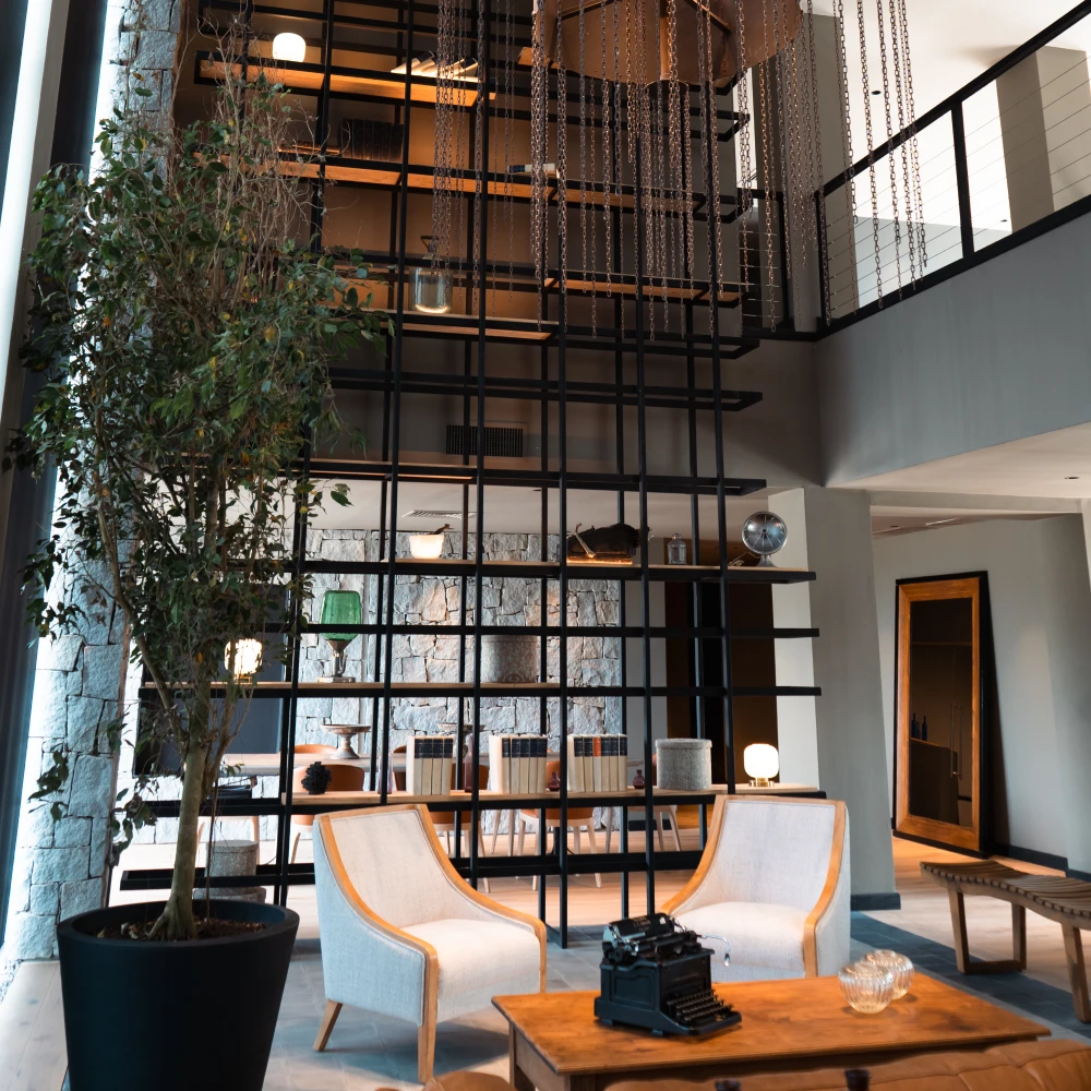 Interior moderno con estanter&iacute;a negra, cadenas colgantes, sof&aacute; y mesa de madera