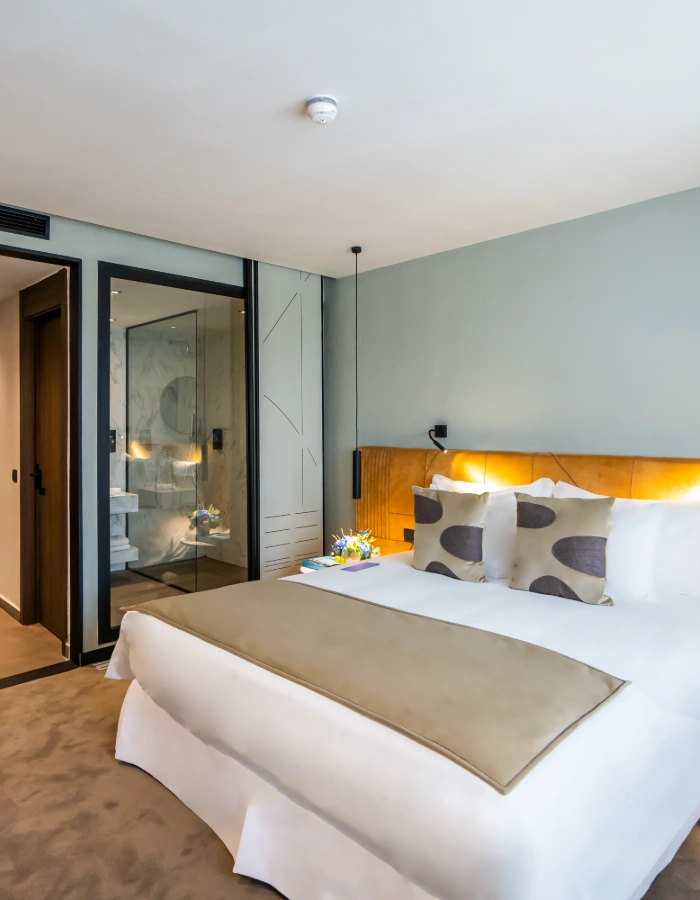 Dormitorio moderno con cama doble, cabecero de madera y cortinas.