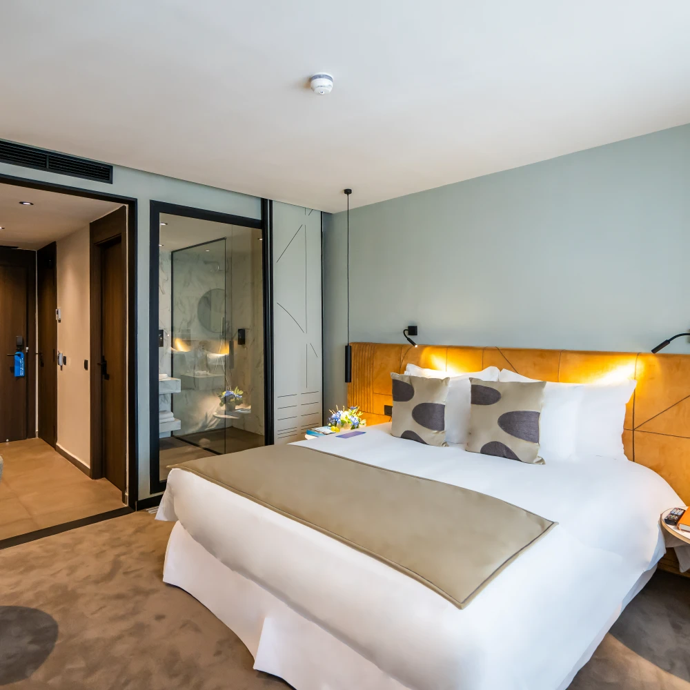Habitaci&oacute;n de hotel moderna con cama doble y puerta de vidrio al fondo