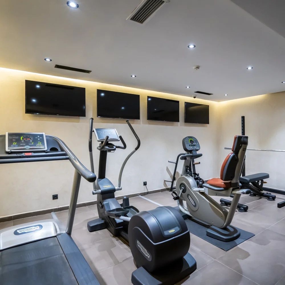 Sala de gimnasio con bicicletas y pantallas de entrenamiento en el muro