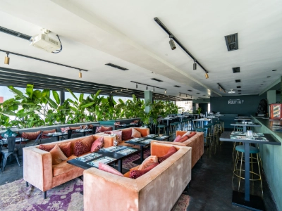 Interior de restaurante moderno con mesas, barra y sof&aacute;s de colores