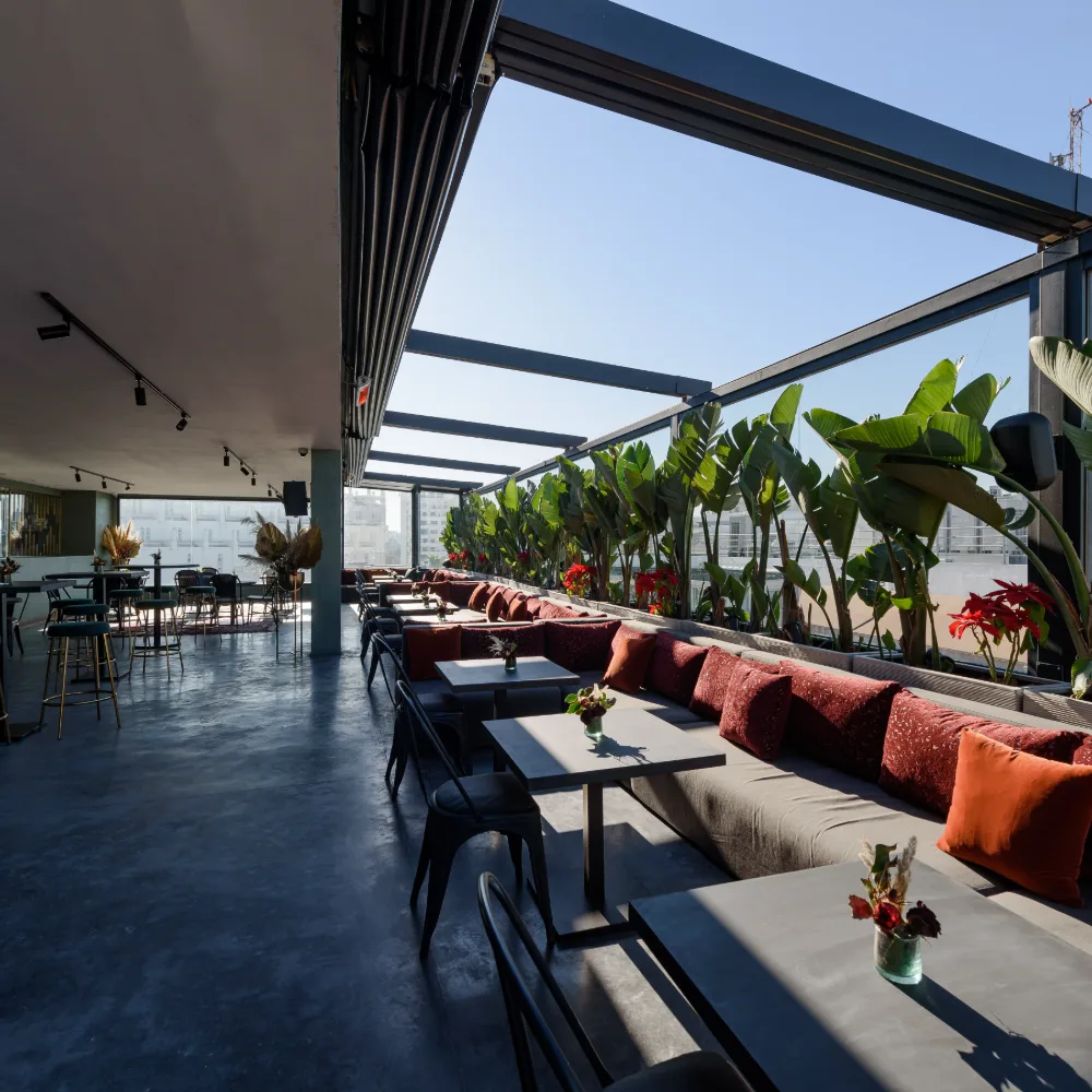 Terraza moderna con mesas, sof&aacute;s y plantas tropicales al aire libre