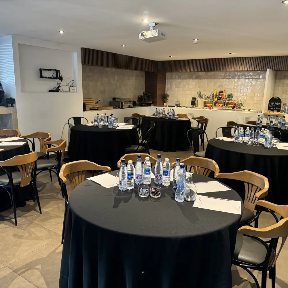 Sala de conferencias con mesas redondas y botellas de agua, estilo moderno.