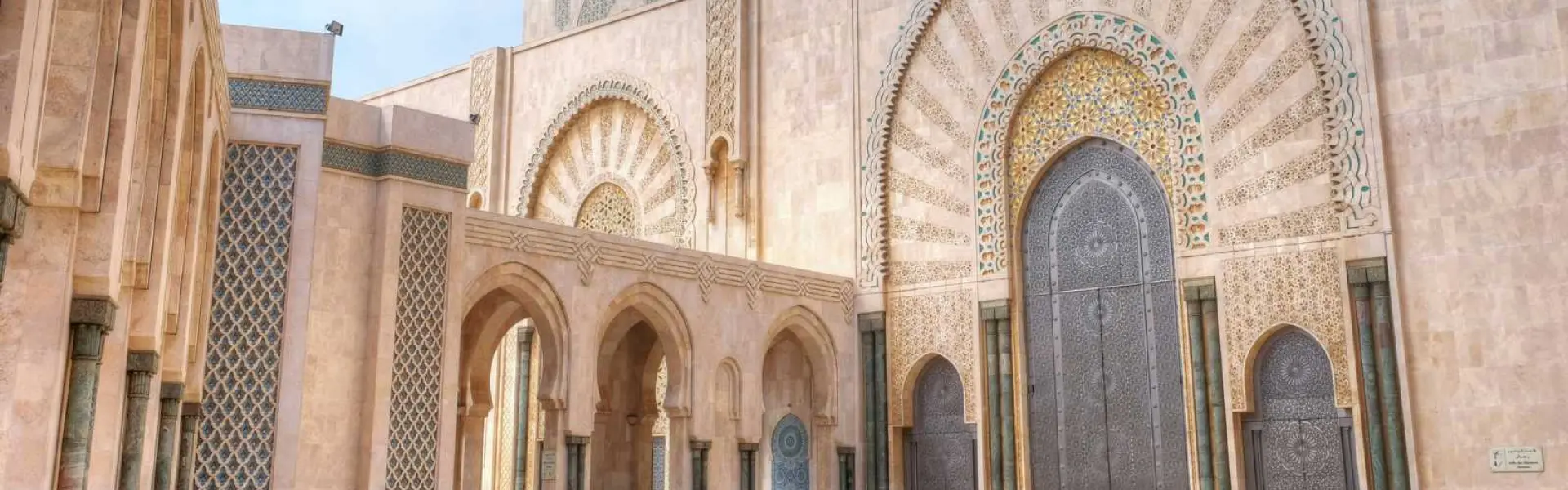 Fachada de mezquita con arco grande, mosaicos y puerta de entrada ornamentada