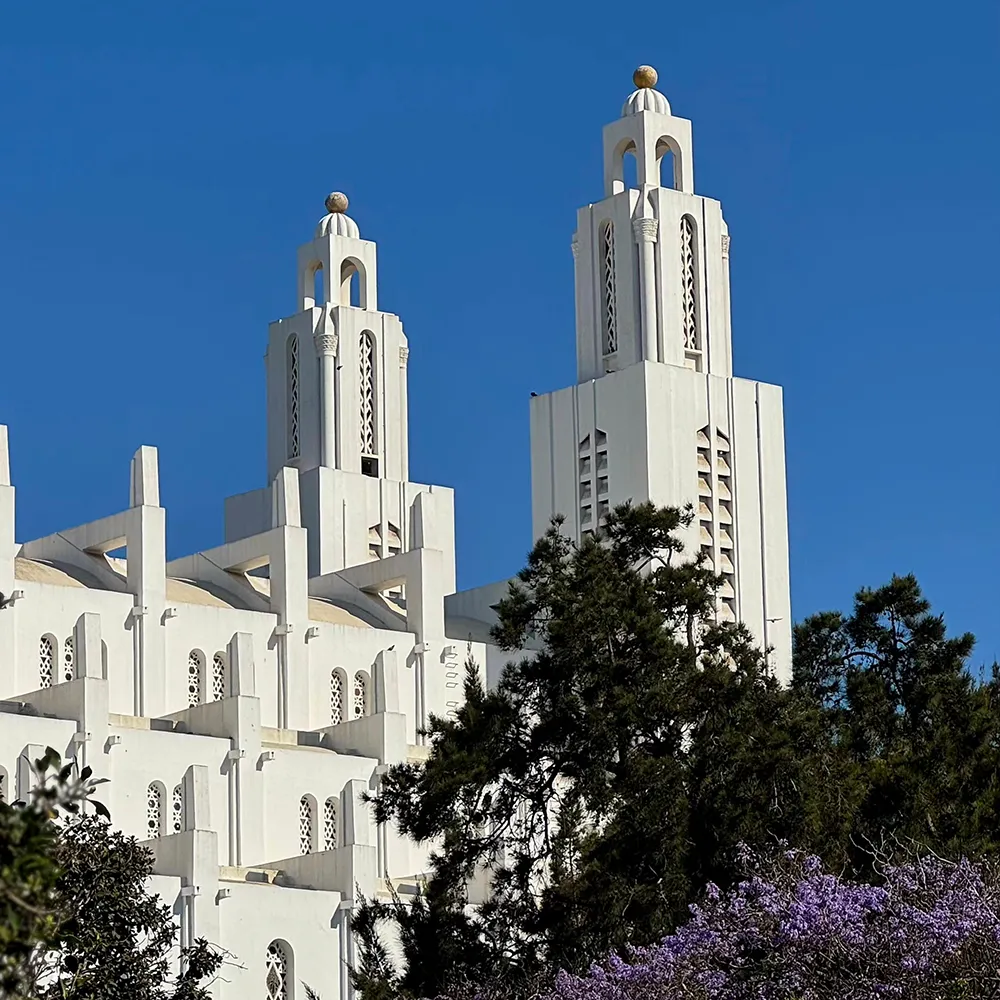 Dos torres de una catedral blanca con cielo azul y &aacute;rboles al frente