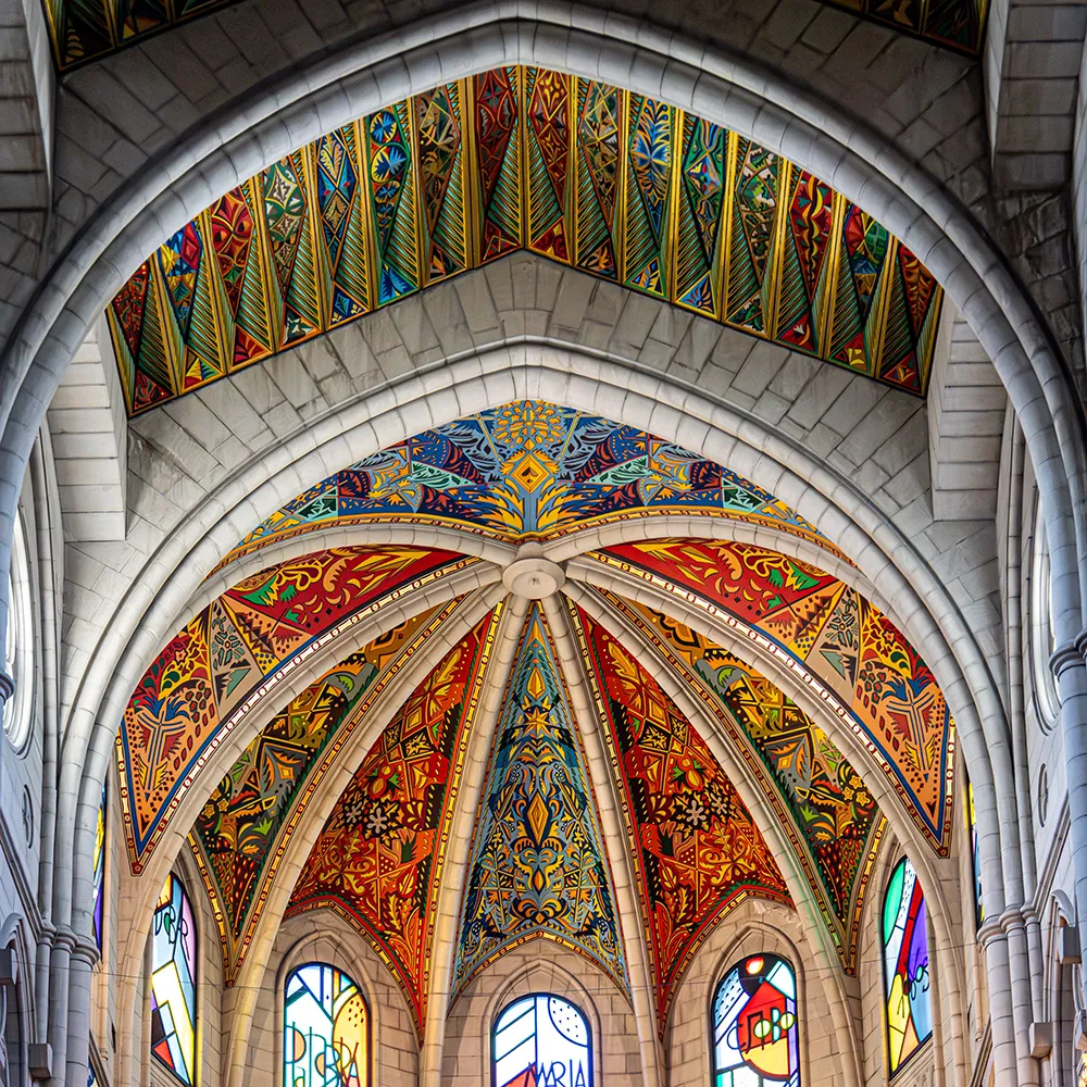 Interior de c&uacute;pula con arcos de piedra y vitrales coloridos y mosaicos decorativos