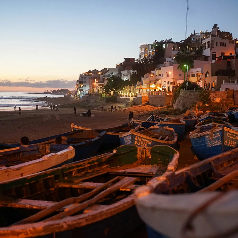 Barcas de pesca y casas blancas al atardecer en la costa del mar.