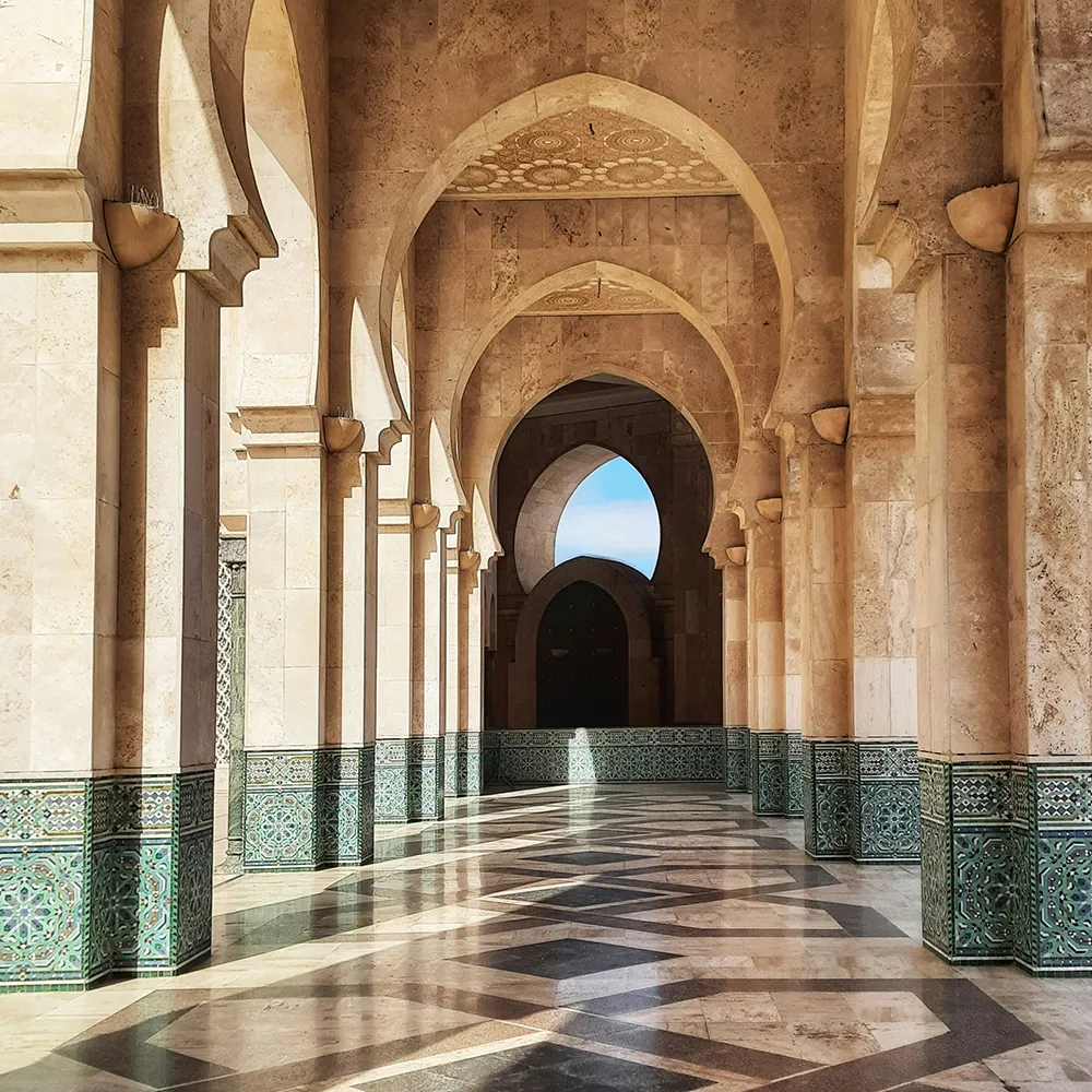 Pasillo con arcos y mosaicos de cer&aacute;mica en un interior de piedra.