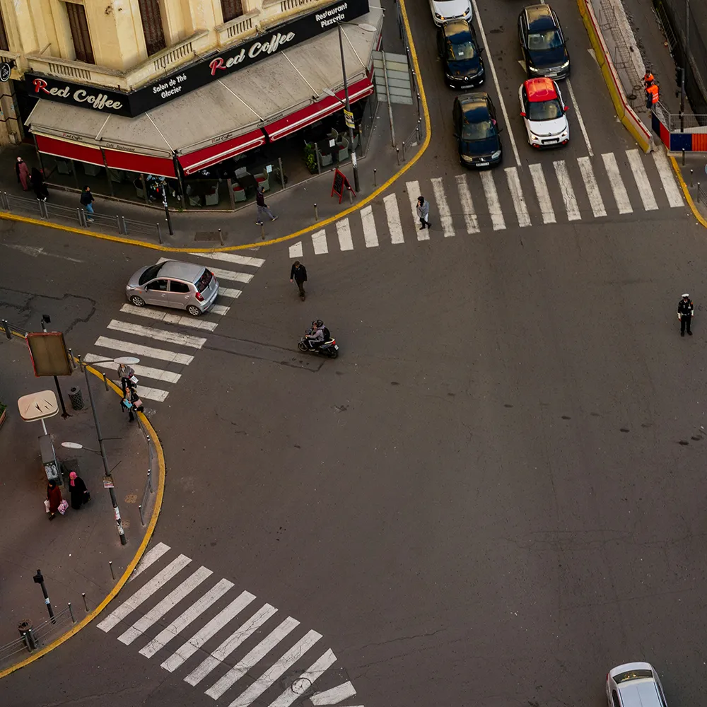 Vista a&eacute;rea de coches, motocicleta y peatones frente a Red Coffee en la calle