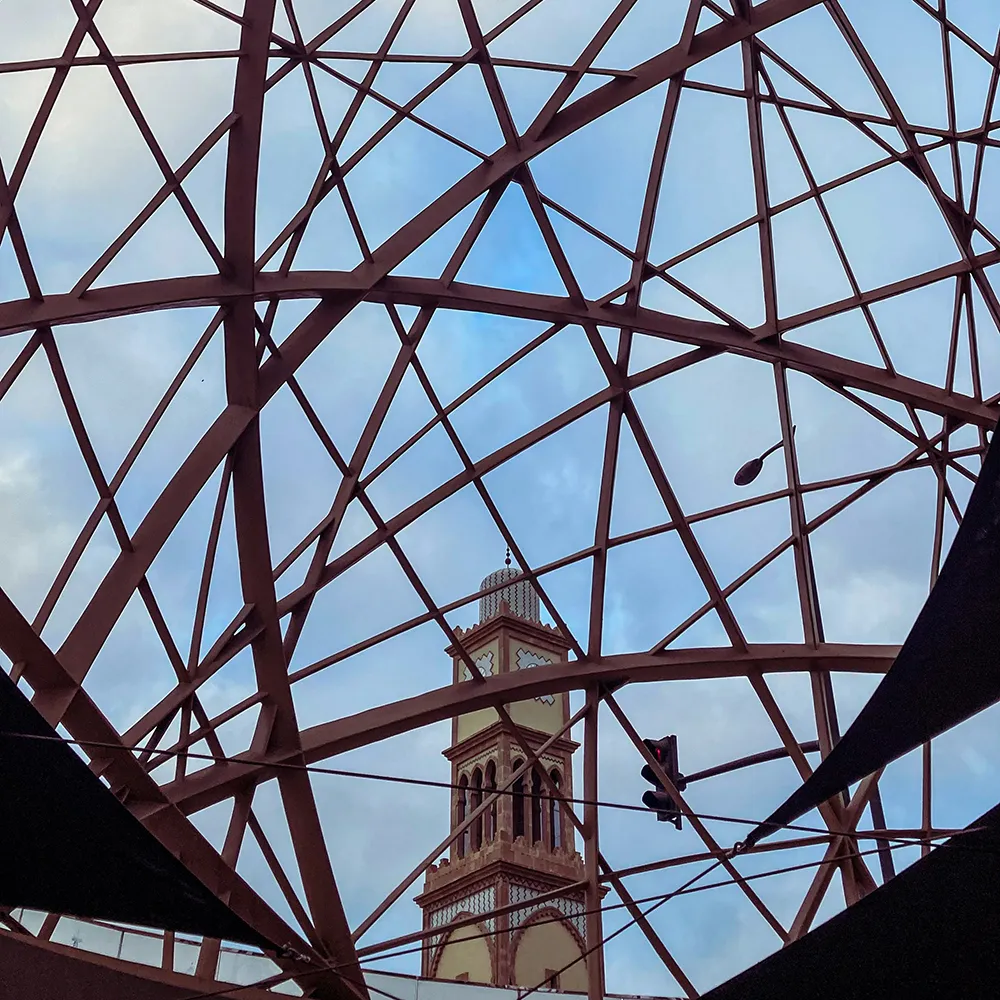 Estructura met&aacute;lica con torre de iglesia y cielo azul detr&aacute;s