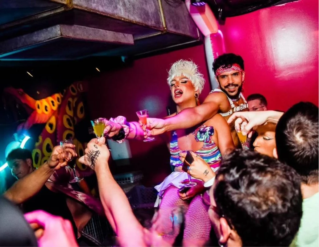 Cantantes con ropa colorida y copas brindando en fiesta nocturna con luces ne&oacute;n