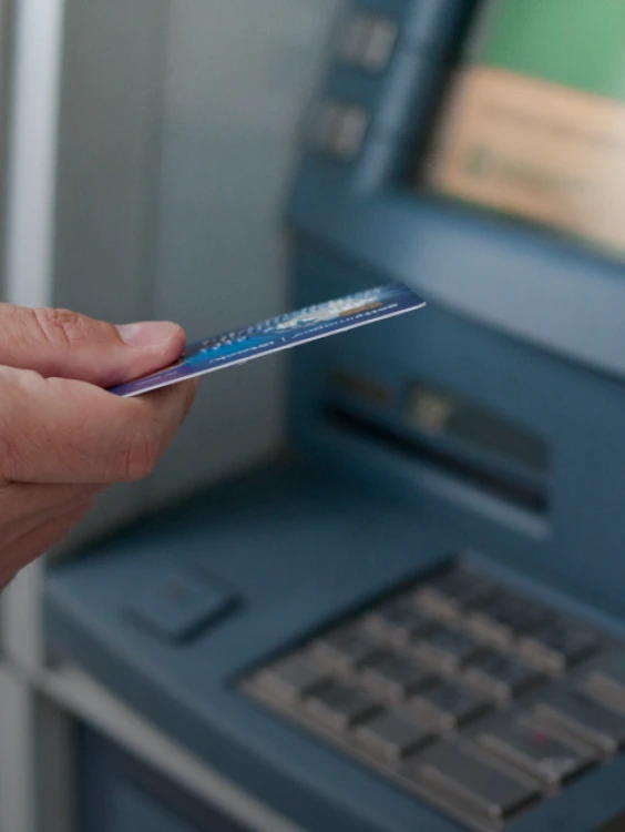 Persona sostiene una tarjeta junto a una m&aacute;quina POS con pantalla.