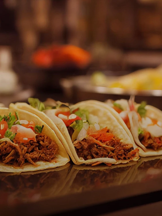 Tacos con carne, tomate y cilantro sobre bandeja, en mostrador caliente