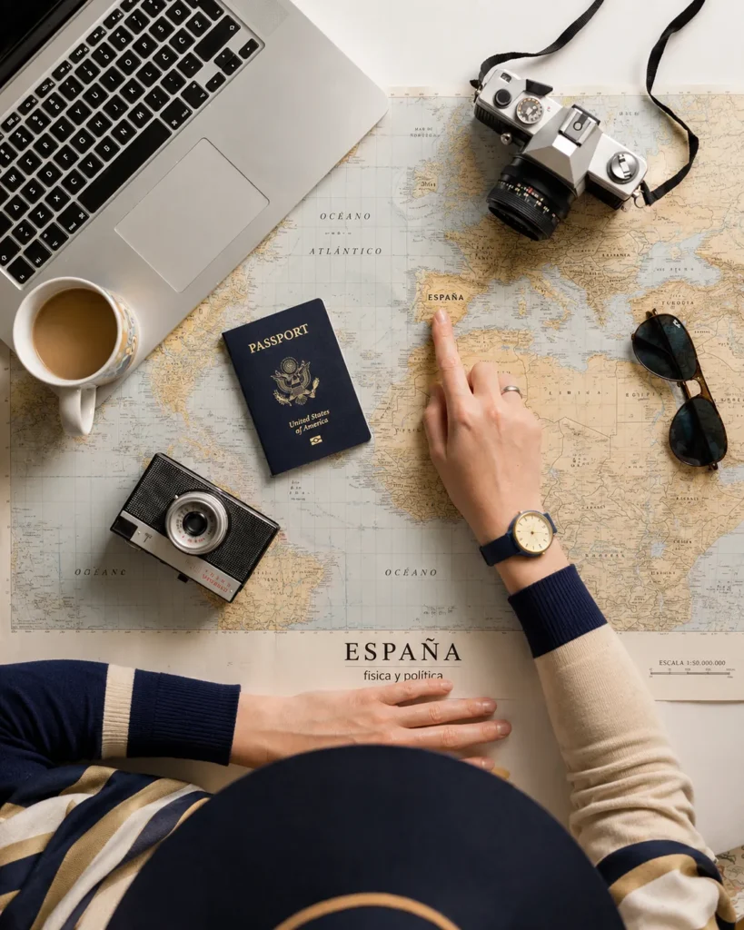Mapa de Espa&ntilde;a con pasaporte y c&aacute;mara, teclado y caf&eacute; sobre escritorio