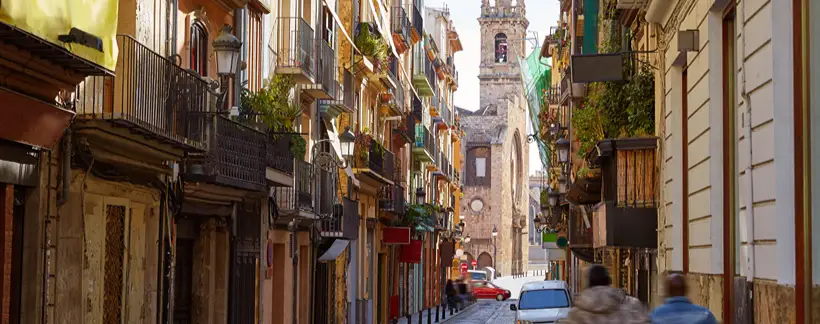 Calle antigua con edificios de colores y la torre de una iglesia al fondo
