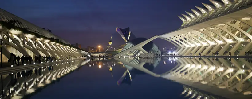 Arquitectura moderna iluminada reflejada en un canal al anochecer