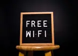 Cartel luminoso &ldquo;FREE WIFI&rdquo; en un marco de madera, sobre fondo oscuro.