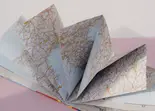 Libro abierto con p&aacute;ginas de mapas y estampas en tonos grises y beige.