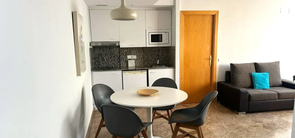 Cocina abierta con mesa redonda y sof&aacute; gris, en un apartamento moderno