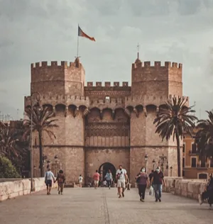 Puerta de entrada de un castillo con banderas y palmeras al frente