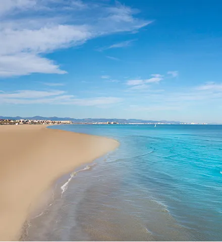Playa de arena dorada con mar azul y cielo despejado.