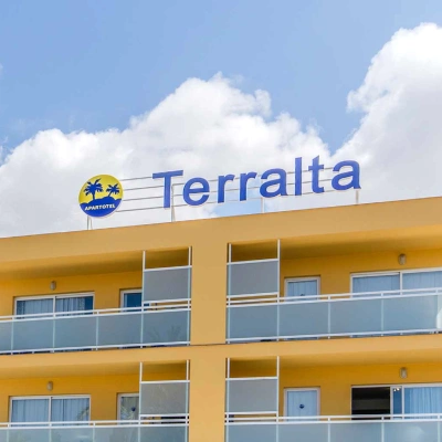 Fachada del hotel Terralta con cielo azul y nubes.
