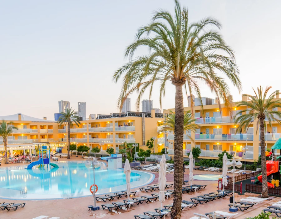 Hotel con piscina al aire libre y palmeras al atardecer