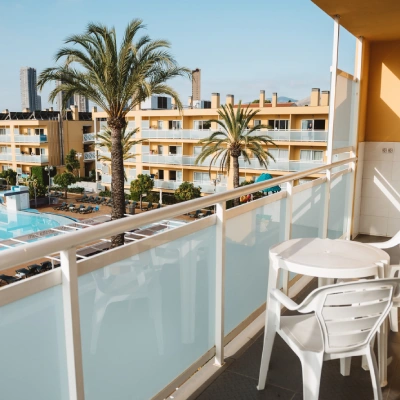 Balcon con vista a piscina y palmeras en complejo vacacional.