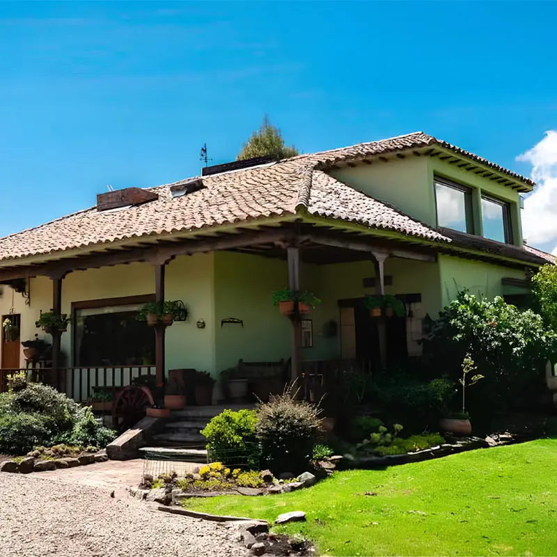 Casa de campo con techo de teja y jard&iacute;n verde bajo cielo azul