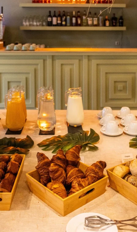 Mesa com croissants, bebidas e velas acesas em bar acolhedor