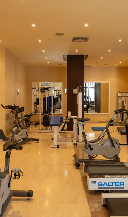 Academia com m&aacute;quinas de cardio e muscula&ccedil;&atilde;o no corredor interior