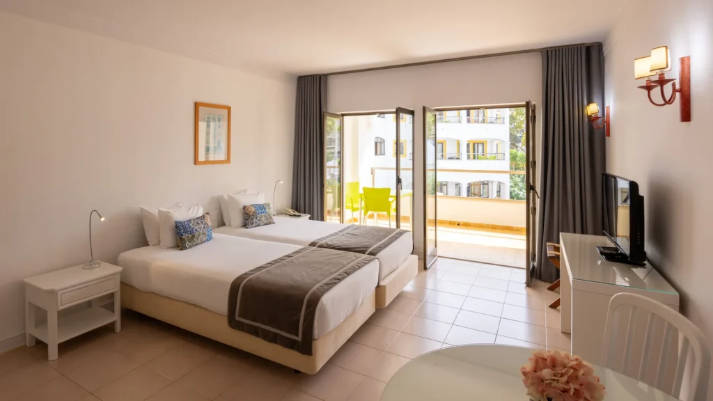 Quarto moderno com camas, varanda e vista para o p&aacute;tio, vista interna.