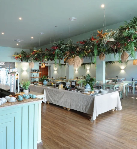Buffet com mesa decorada e arranjos verdes em ambiente de restaurante