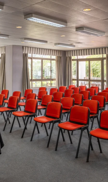 Sala com cadeiras vermelhas e janelas amplas com luz natural