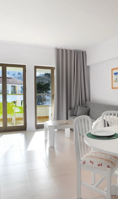 Sala de estar com mesa e cadeiras perto de portas de vidro e cortinas cinzas