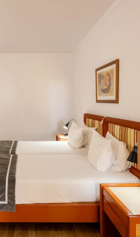 Quarto com cama de madeira, travesseiros brancos e abajur.