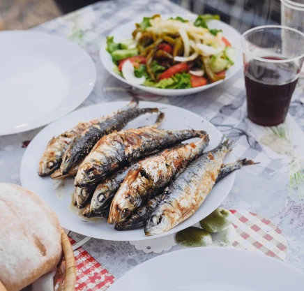 Peixe grelhado com salada e p&atilde;o em mesa posta ao ar livre