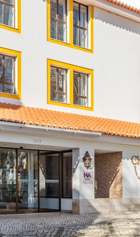 Fachada de pr&eacute;dio com janelas coloridas amarelas e telhado de telhas.
