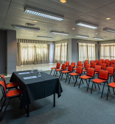 Sala de reuni&atilde;o com cadeiras vermelhas e mesa central em ambiente corporativo